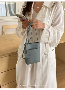 Minimalistische hellblaue Handy-Leder-Umhängetasche mit geflochtenem Tragegriff.