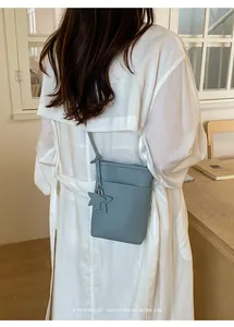 Minimalistische hellblaue Umhängetasche für das Handy mit Sternanhänger am Model getragen.