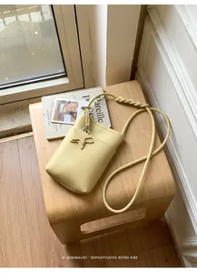 Detailansicht einer hellgelben minimalistischen Handytasche mit Sternanhänger auf Hocker