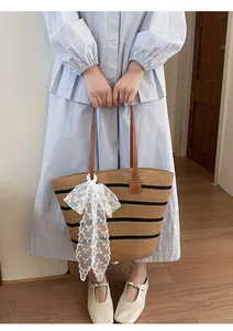 Detalle de bolso tote de paja tejido a mano con un elegante lazo de encaje blanco