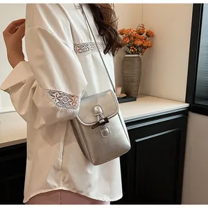Stylish silver crossbody phone bag worn over a white lace top in a modern home setting