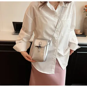 Stylish silver metallic phone crossbody bag worn by a model in a casual indoor setting.
