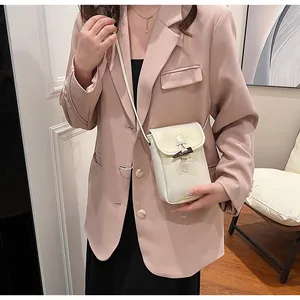 Model wearing a stylish off-white crossbody phone bag with a black toggle closure.