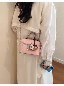 Elegante kleine quadratische Handtasche in Rosa mit Schaukelpferd-Anhänger getragen