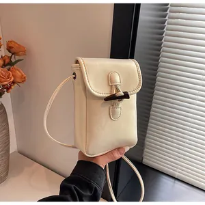 Detailed view of a cream white minimalist crossbody phone bag featuring a stylish toggle closure