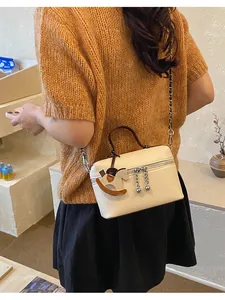 Modell mit schicker beiger Leder-Umhängetasche und einem einzigartigen Schaukelpferd.