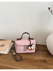 Elegante Handtasche aus rosa Leder mit Kettenriemen und Schaukelpferd-Anhänger am Schreibtisch