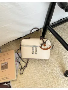 Detailansicht einer beigen Lederhandtasche mit Schaukelpferd-Anhänger und Kette