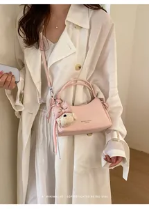Detailed view of a pink leather crossbody bag with a cute bear charm and bow