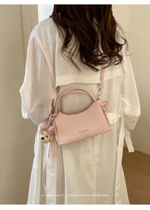 Elegant pink crossbody handbag shown with cute bear charm and adjustable shoulder strap
