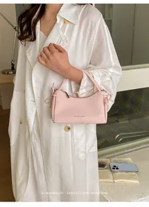 Detailed view of a trendy pink mini handbag styled with a white minimalist linen coat.