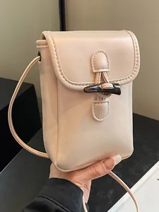 Minimalist cream small crossbody phone bag featuring a stylish horn toggle button closure