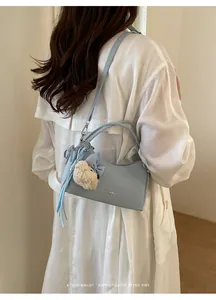 Model wearing light blue small crossbody square bag with cute teddy bear charm