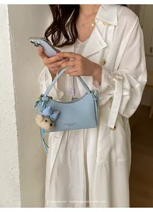 Stylish light blue leather underarm handbag with cute bear charm and minimalist retro vibe