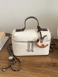 Elegante cremefarbene Leder-Box-Tasche mit goldener Kette und Pferdeanhänger