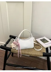 Minimalist white crossbody handbag featuring a cute plush bear charm on a woven chair