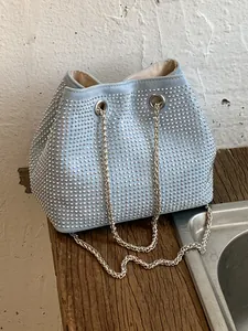Stylish light blue bucket bag with silver studs and chain strap decoration.