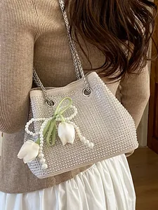 Elegant beige rhinestone bucket bag featuring a tulip pearl pendant and silver chain straps