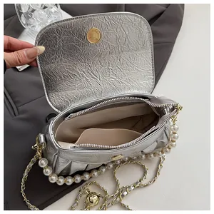 Vista dettagliata della borsa a mano plissettata argento con catena di perle e fodera