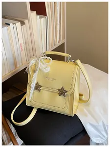Dettaglio di uno zaino giallo da donna con fibbie a stella e decorazione in pizzo.