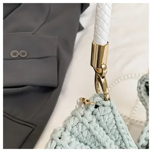 Close-up detail of woven texture and gold-tone metal clasp on a shell-shaped bag