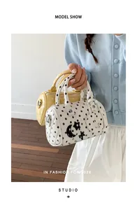 Vue détaillée de sacs Boston à pois blancs et jaunes portés par un mannequin en studio.