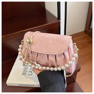 Dettaglio ravvicinato della borsa a mano plissettata rosa con elegante tracolla in perle e oro
