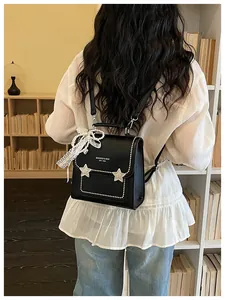 Dettaglio di uno zaino nero alla moda con borchie a stella e fiocco di perle sul retro