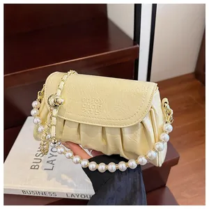 Dettaglio della borsa a mano plissettata giallo chiaro con elegante manico in perle