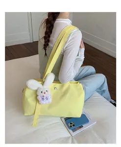Large yellow nylon tote bag with cute plush rabbit charm shown in lifestyle setting