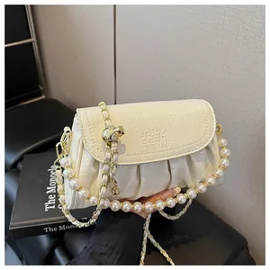 Dettaglio borsa a mano plissettata bianco crema con catena di perle e dettagli oro.