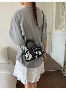 Sac Boston à pois noir et blanc porté en bandoulière par un mannequin dans une pièce
