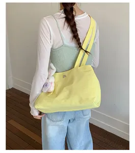 Back view of a woman carrying a large yellow nylon tote bag with a plush bunny.