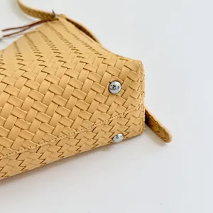 Detailansicht einer gelben handgewebten Eimertasche aus Leder mit silbernen Metallfüßen