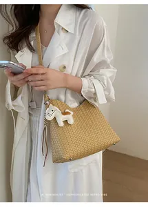 Detailansicht einer beigen geflochtenen Hobo-Tasche mit Pferdeanhänger an einem Modell.
