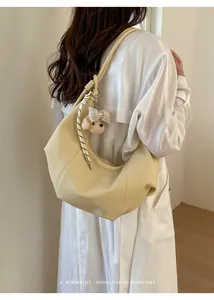 Close-up back view of a woman styling a light yellow retro hobo bag with a dog charm