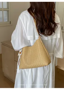 Rückansicht einer eleganten cremefarbenen gewebten Unterarmtasche zu einem weißen Kleid