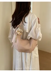 Stylish pink pleated hobo bag with cute teddy bear charm worn by model from behind