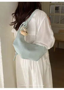 Detail of a light blue pleated hobo bag with a cute bear charm and white outfit