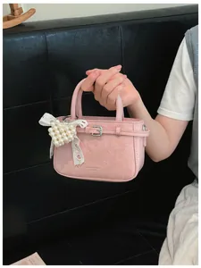 Close-up detail of a pink leather mini handbag with a heart pearl and lace bow