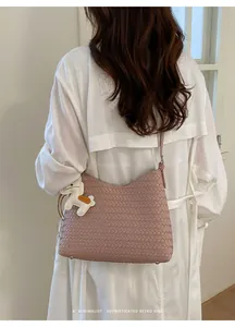 Schicke rosa gewebte Umhängetasche mit Tiermotiv-Anhänger am Model im Retro-Vibe.