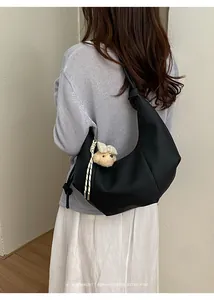 Back view of a black pleated hobo bag worn by a model in a minimalist setting.