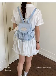 Fashionable light blue canvas backpack with star prints worn by a model in a studio