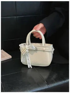 Detailed view of cream textured leather handbag with elegant pearl heart pendant charm