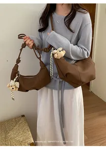 Lifestyle shot of a brown retro pleated hobo bag with a cute teddy bear charm detail