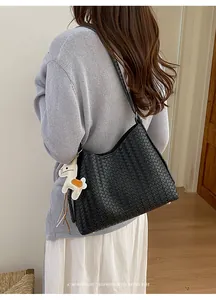Detaillierte Rückansicht einer schwarzen gewebten Schultertasche an einem Model.
