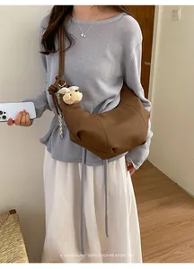 Detailed view of a brown pleated hobo bag worn by a model in a minimalist room