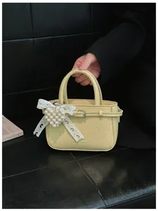 Detail of cream yellow bucket bag with wrinkled leather texture and pearl heart charm