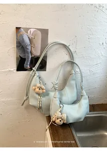 Light blue minimalist hobo bag featuring pleated texture and a cute bear charm accessory.
