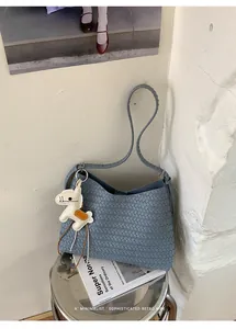Detailaufnahme einer blauen gewebten Unterarm-Beuteltasche mit süßem Pferdeanhänger-Zubehör